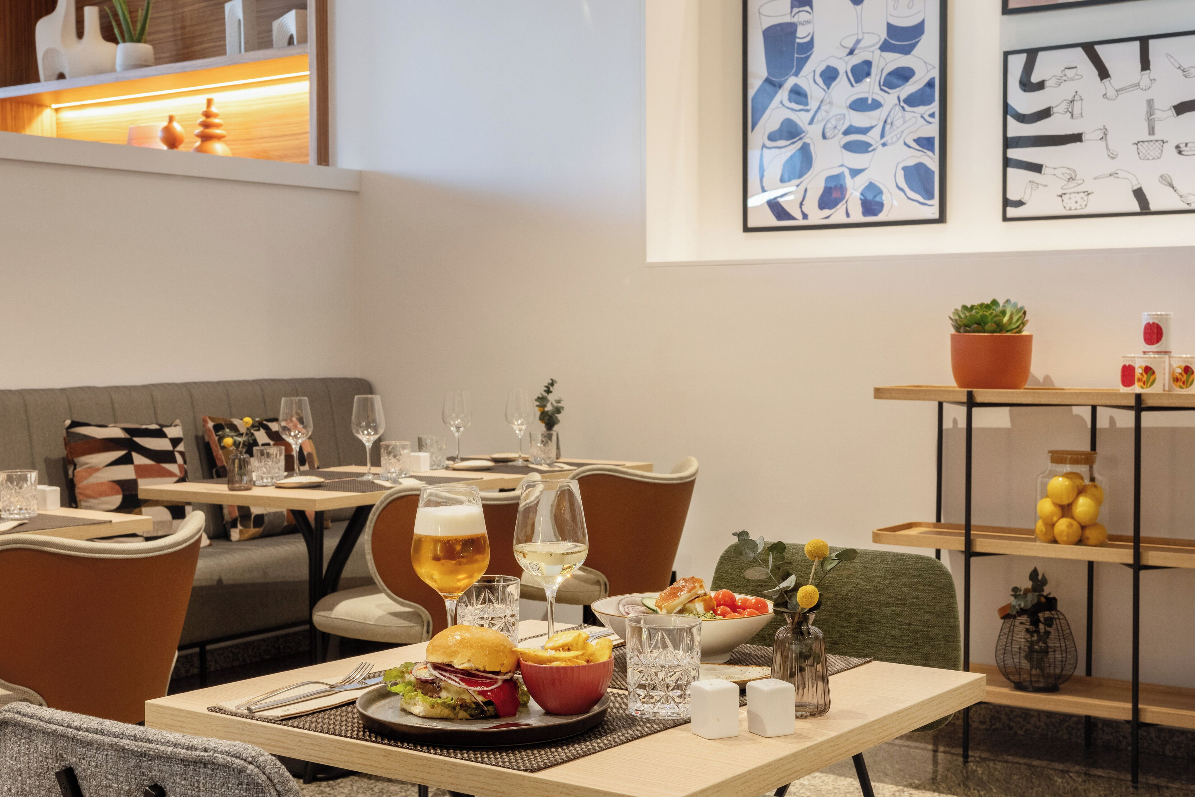 Un comedor con una mesa dispuesta para dos personas, que incluye comida, vasos y una planta en maceta.
