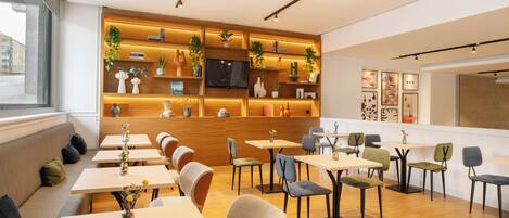 A modern cafe with wooden shelves, comfortable seating, and a TV screen.