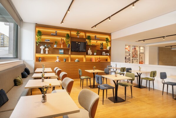 Un café moderno con estantes de madera, asientos cómodos y una pantalla de televisión.