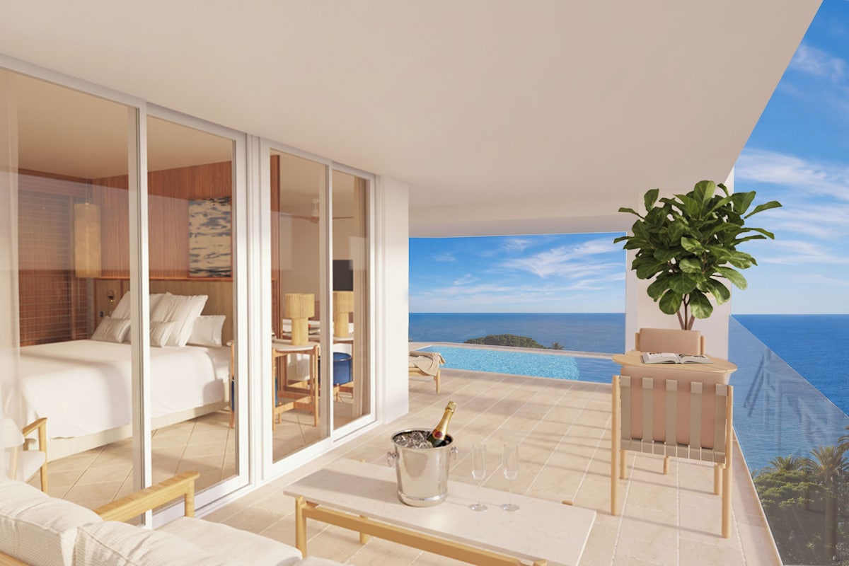 A modern hotel room with a large sliding glass door leading to a balcony with a pool and ocean view.