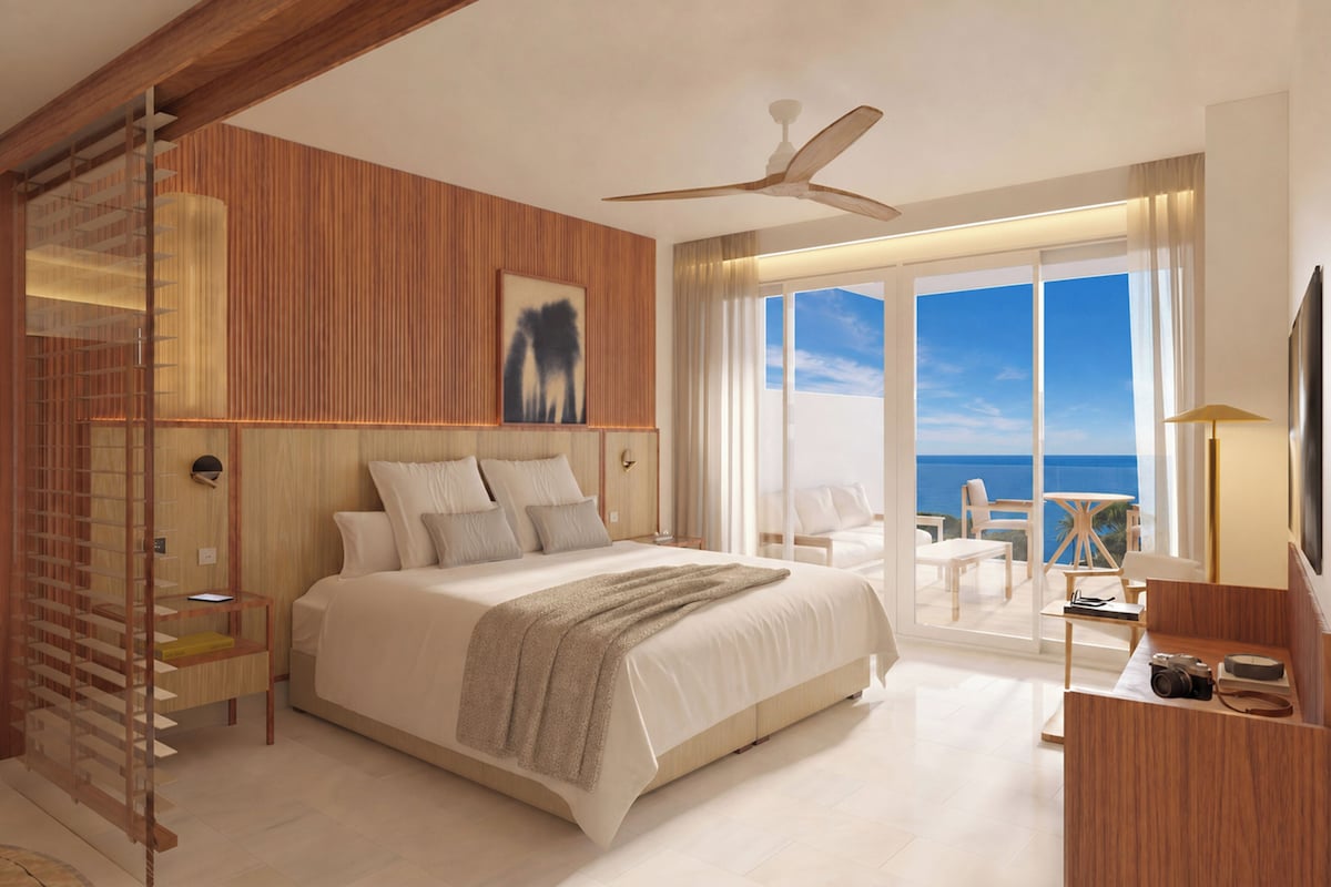 Un dormitorio moderno con una cama grande, un ventilador de techo y vistas al océano.