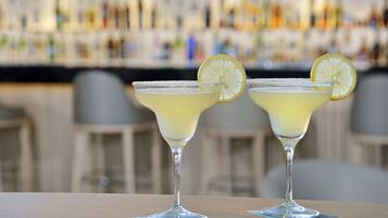Dos margaritas con rodajas de limón sobre una barra.