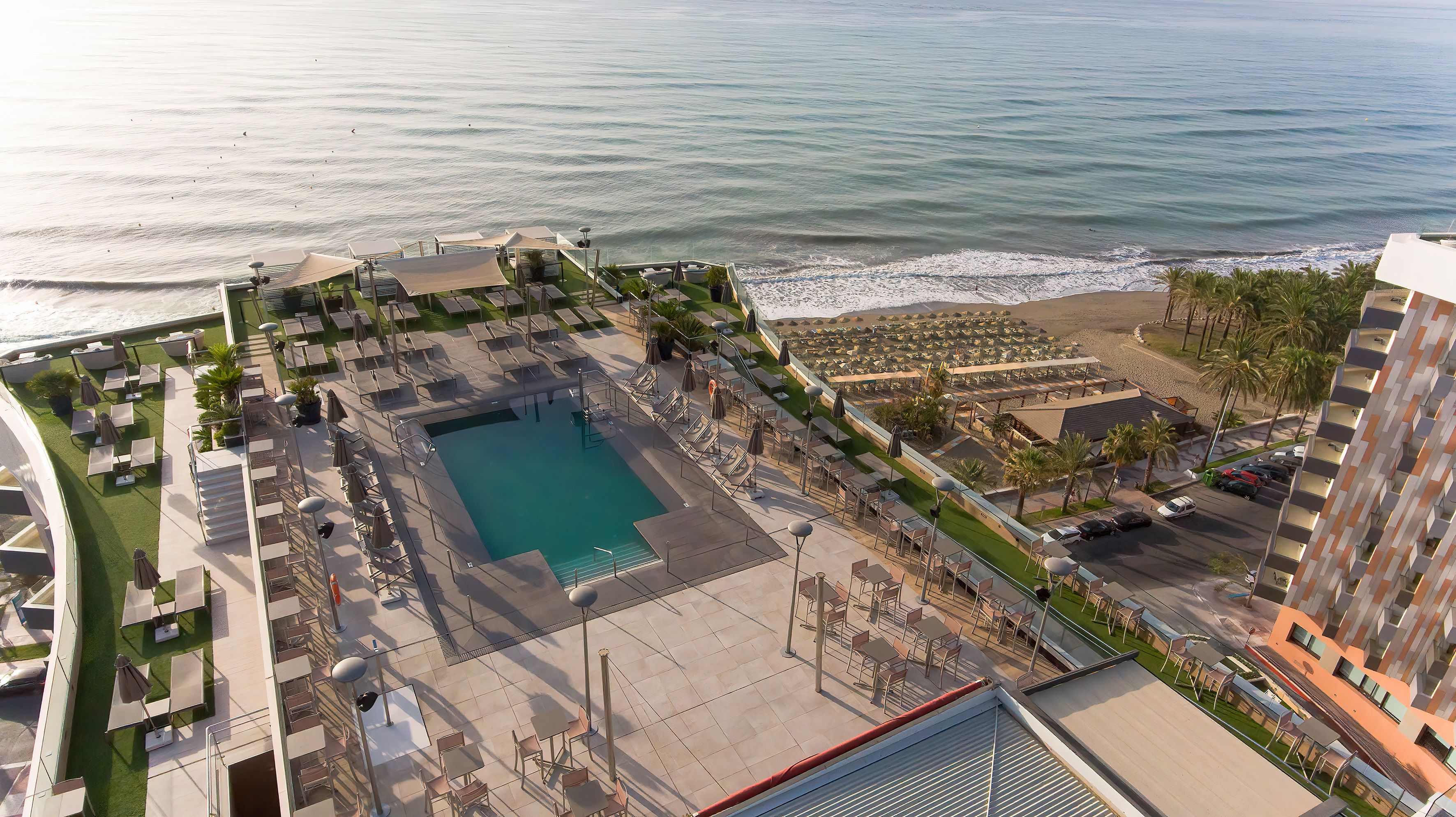 Un resort con piscina, sillas de descanso y vista al océano.