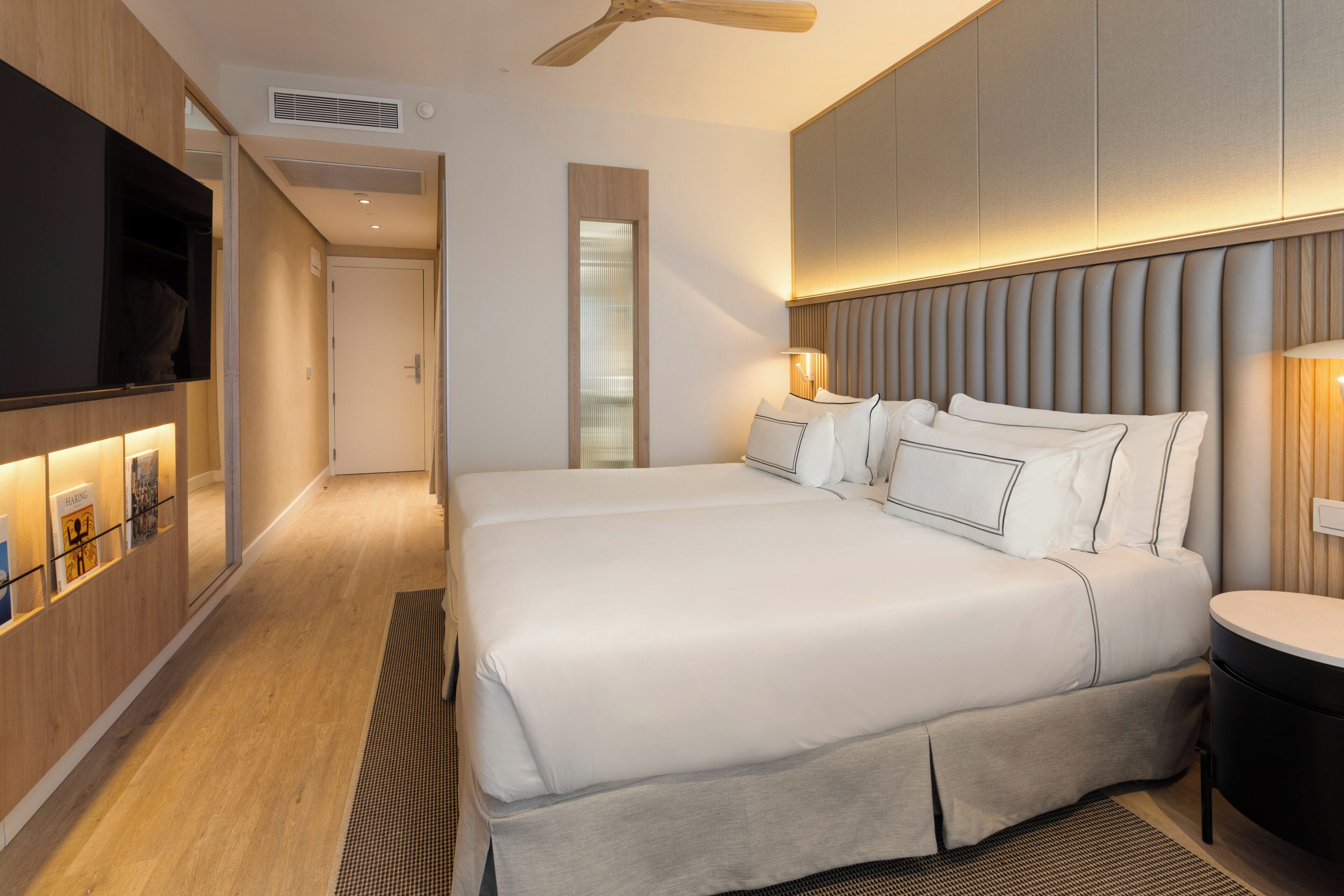 Une chambre d’hôtel moderne dotée d’un grand lit, d’un téléviseur à écran plat et d’un bureau avec une chaise.