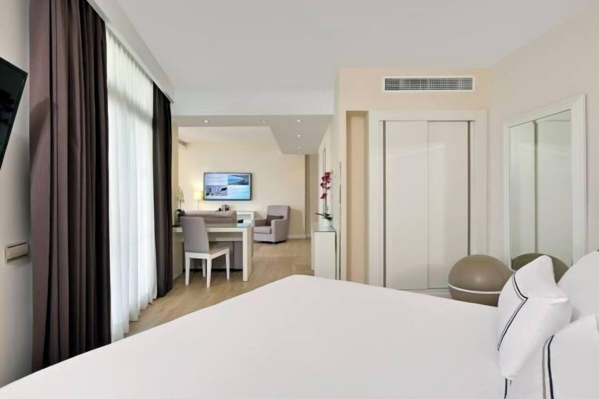 Una habitación de hotel con cama, un escritorio, una silla, un televisor y una puerta.