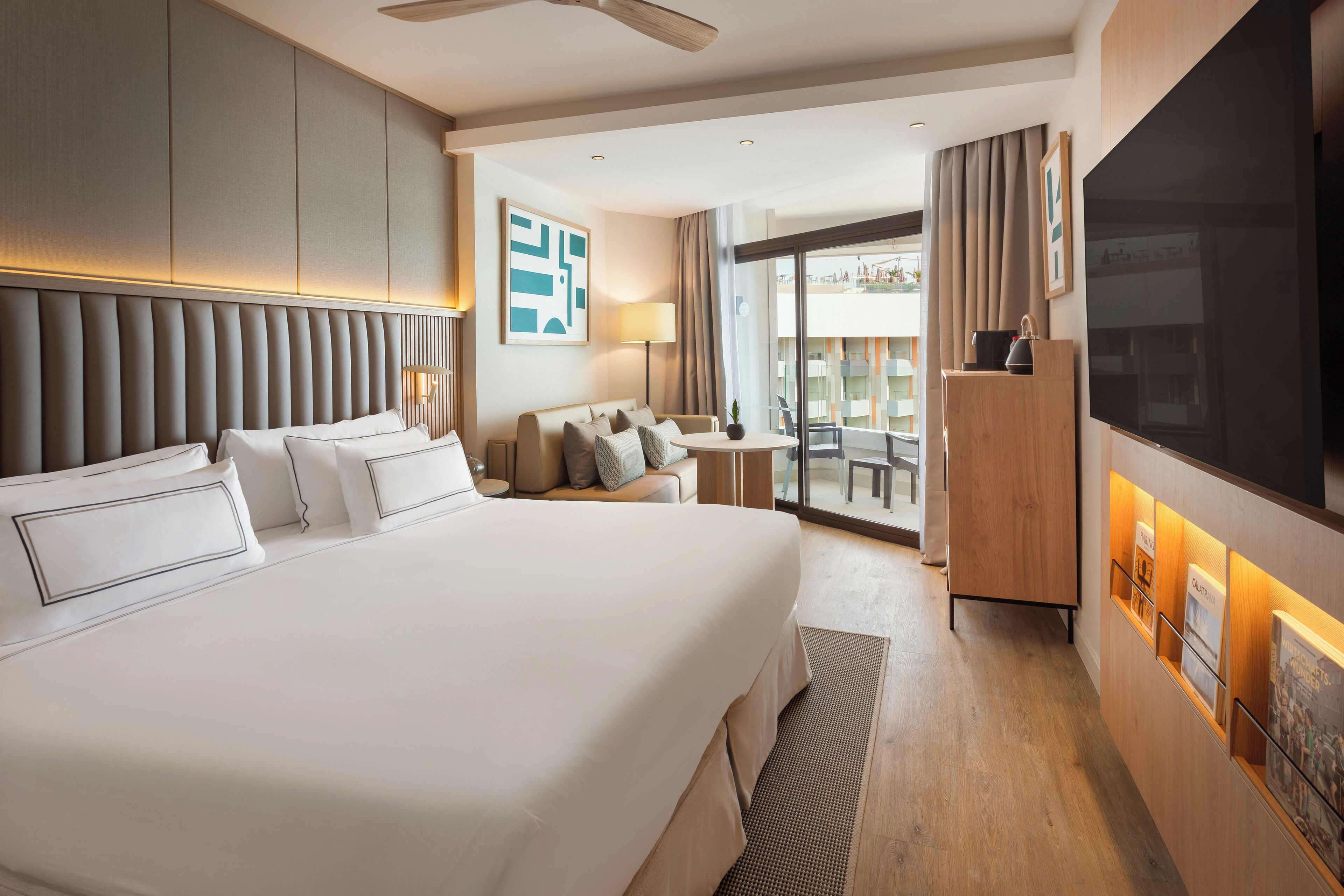 Una habitación de hotel moderna con una cama grande, un sofá, un escritorio y un televisor.