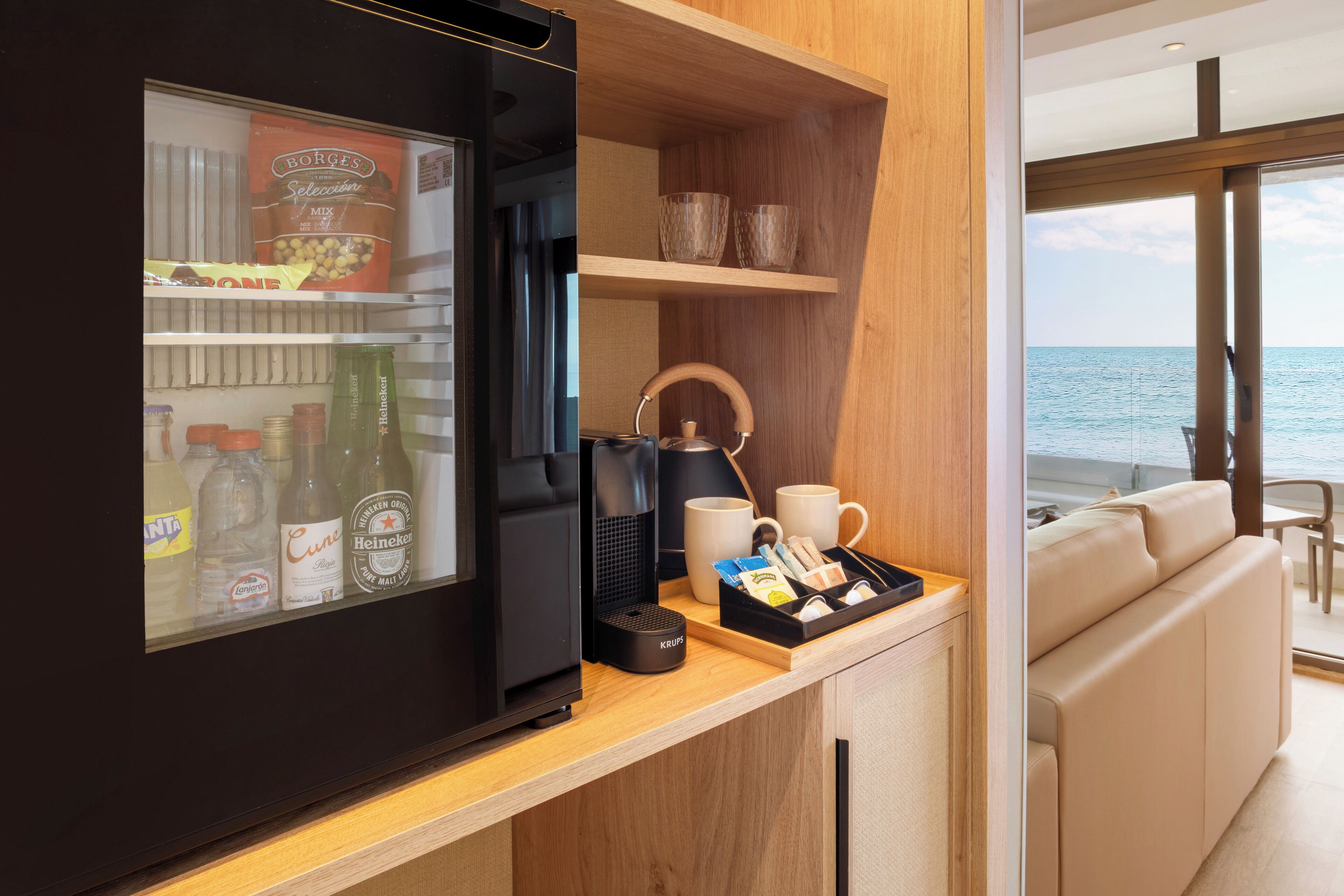 Une petite cuisine équipée d’un réfrigérateur, d’une machine à café et de diverses boissons.
