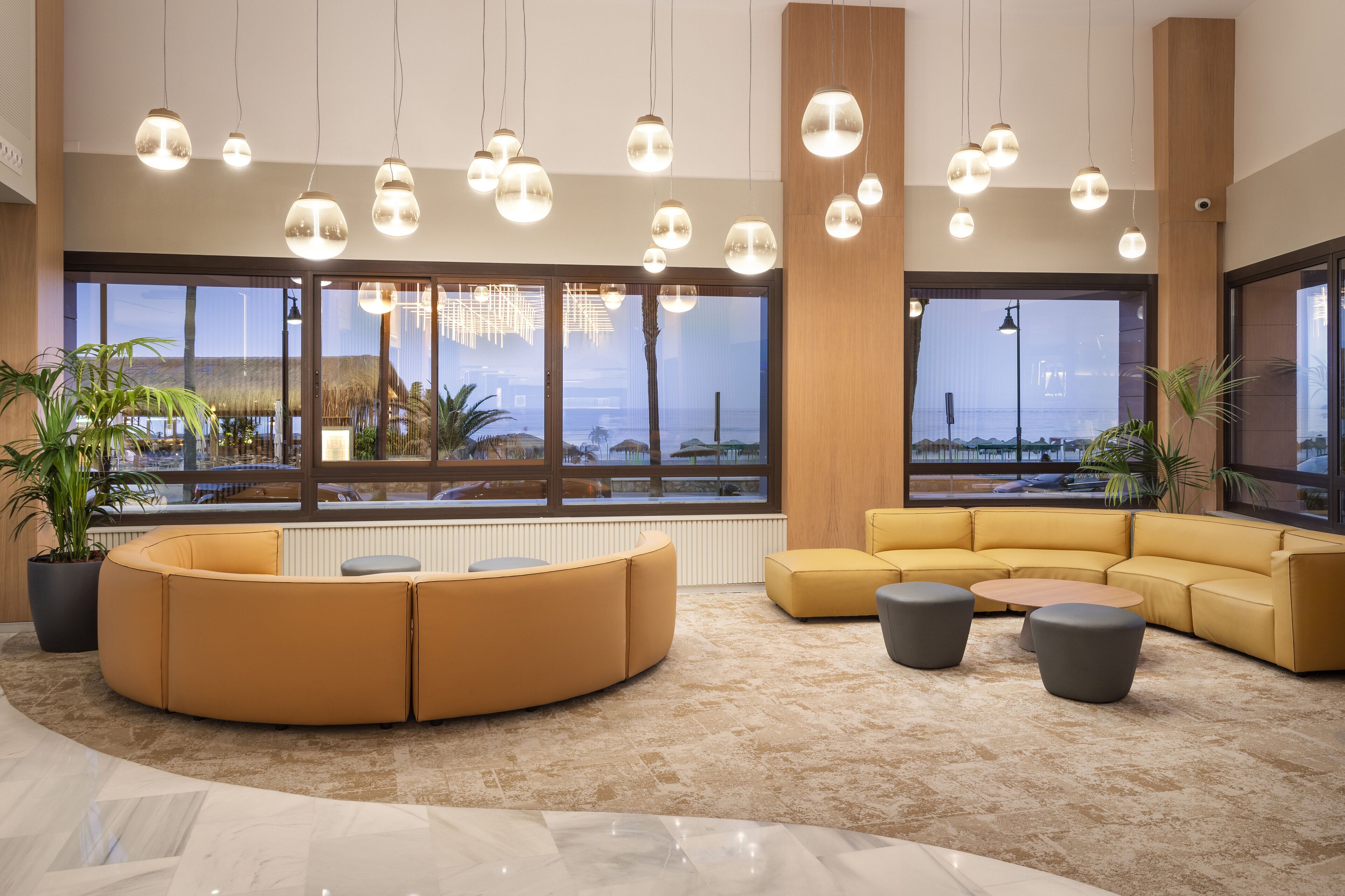 A modern lobby with a curved sofa, a round coffee table, and pendant lighting.
