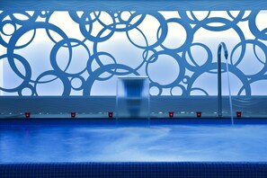 Una piscina con diseño moderno, que presenta un patrón geométrico en la pared y una superficie de agua cristalina.