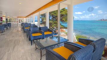 A spacious indoor area with a glass wall offering a view of the sea and a city skyline.