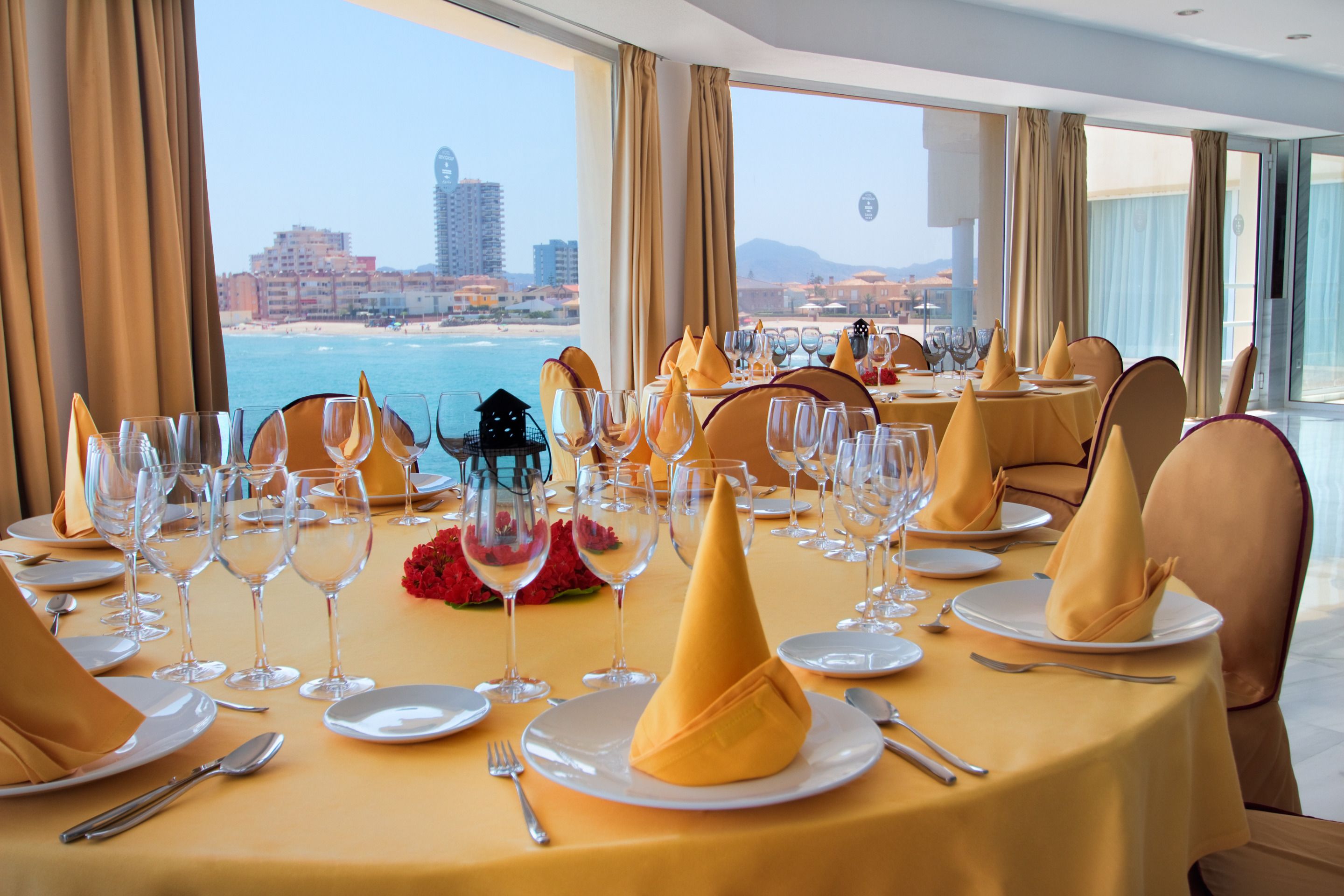 Una mesa de comedor lista para una comida, con vista a la playa y al paisaje urbano.