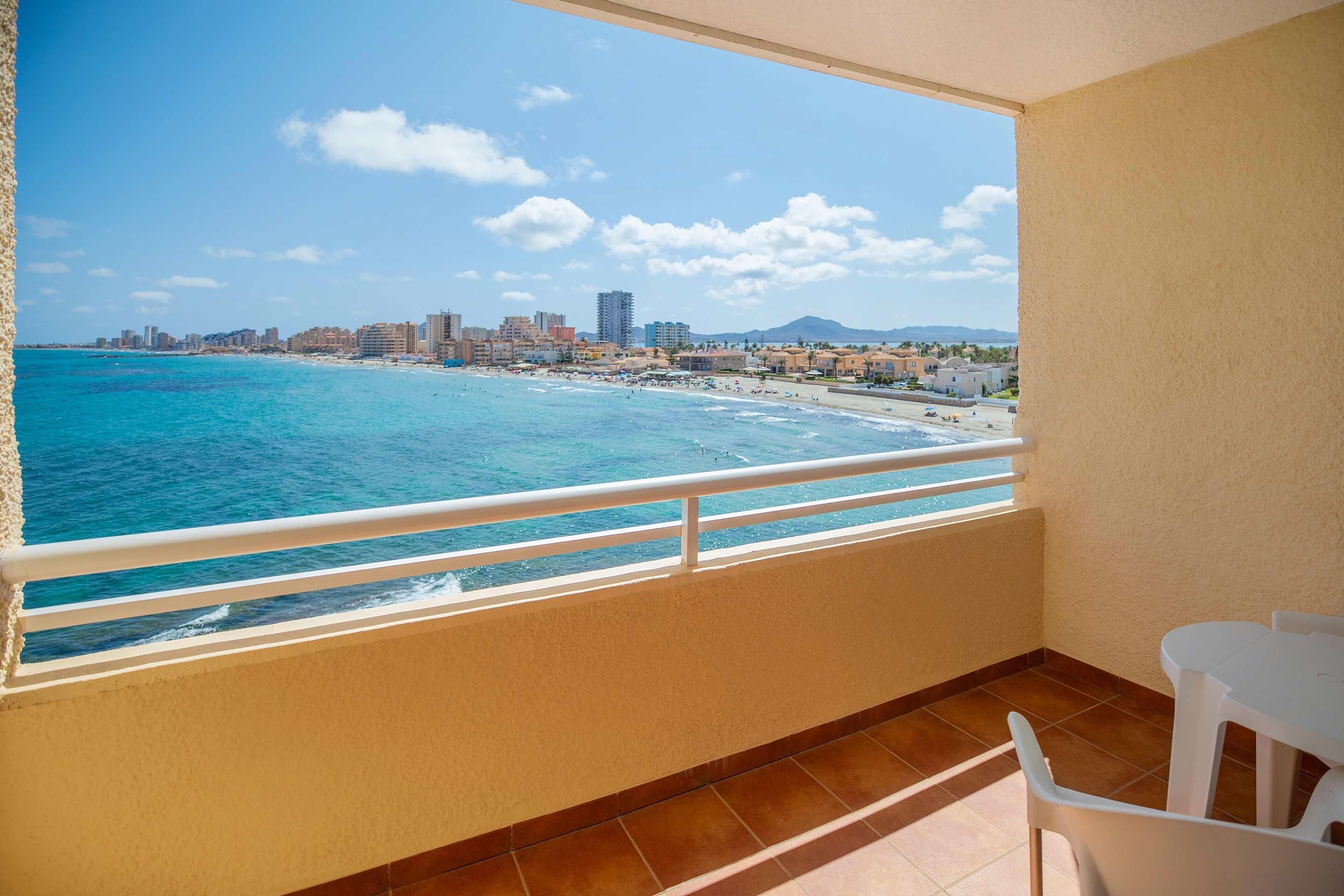 A balcony with a view of a beach and cityscape.