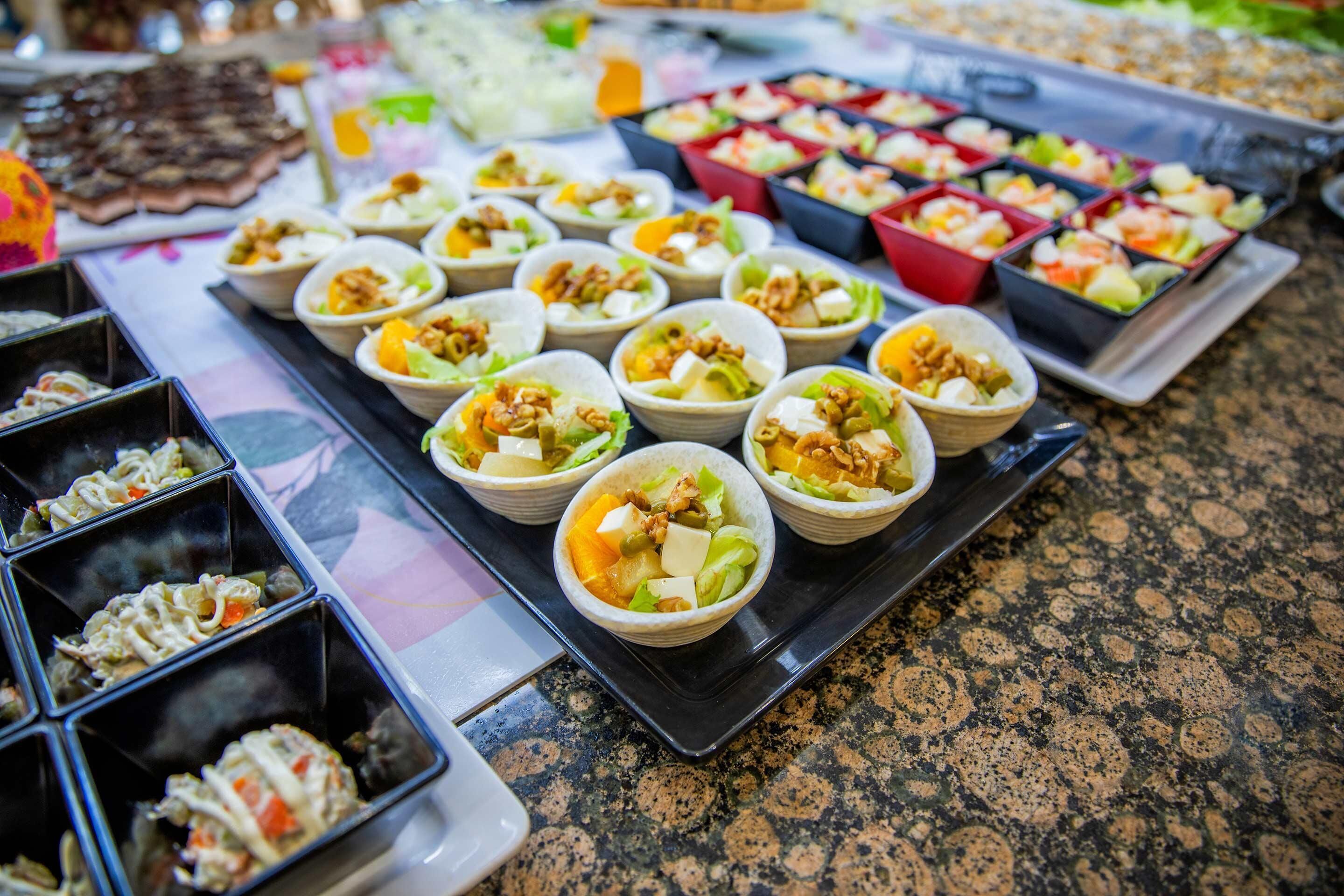 A buffet table with various food items, including bowls of salad and other dishes.