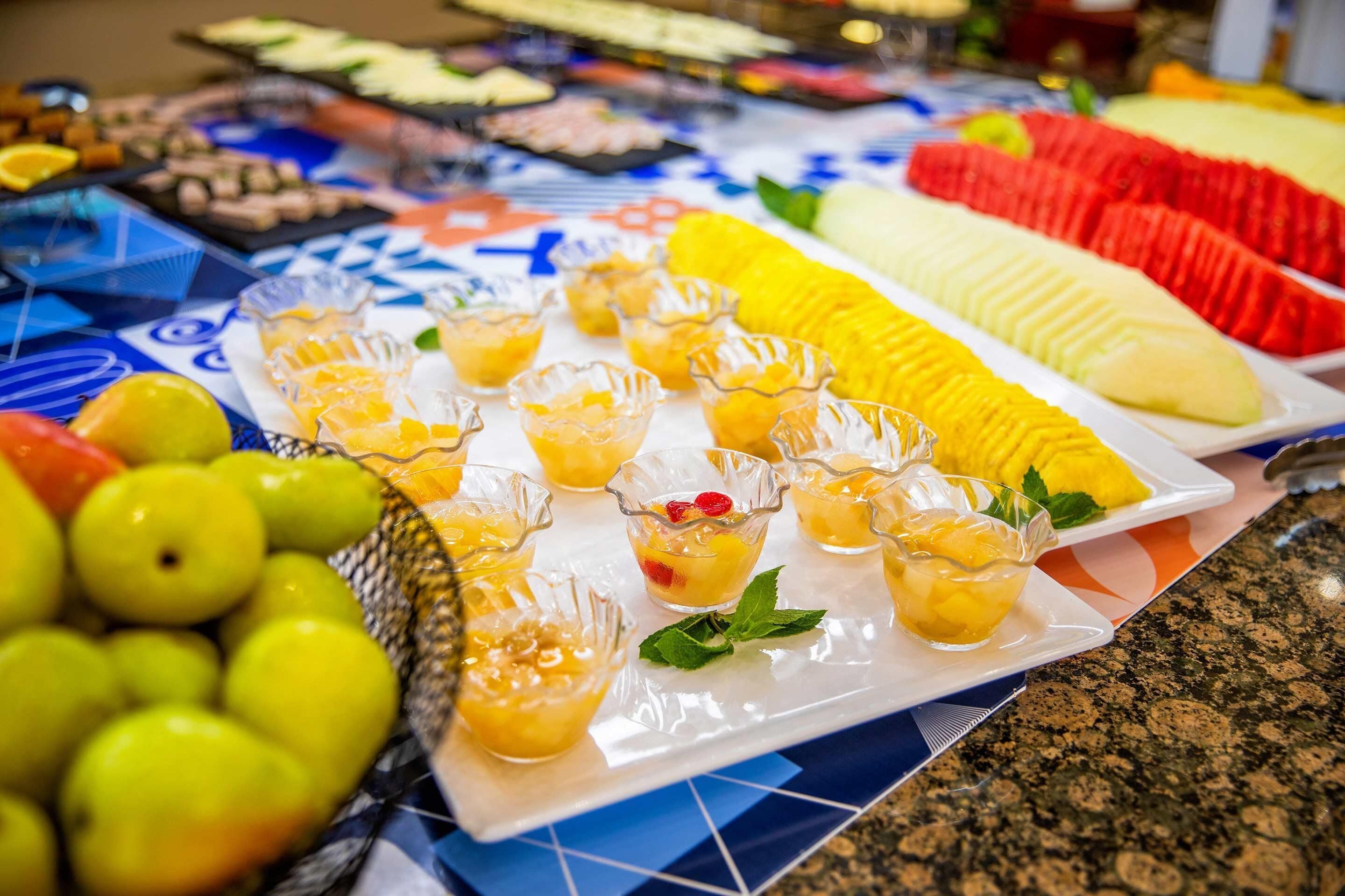 Un bufé con diversas frutas y bebidas.