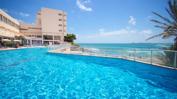 Una piscina al aire libre, sombrillas, sillones reclinables de piscina