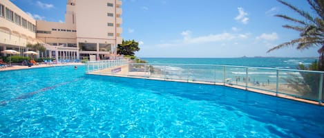 Una piscina al aire libre, sombrillas, sillones reclinables de piscina