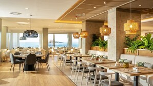 A modern restaurant with multiple dining tables and chairs, large windows with a view of the sea, and hanging wicker lamps. - INNSiDE by Meliá Costablanca - Adults recommended (Benidorm)