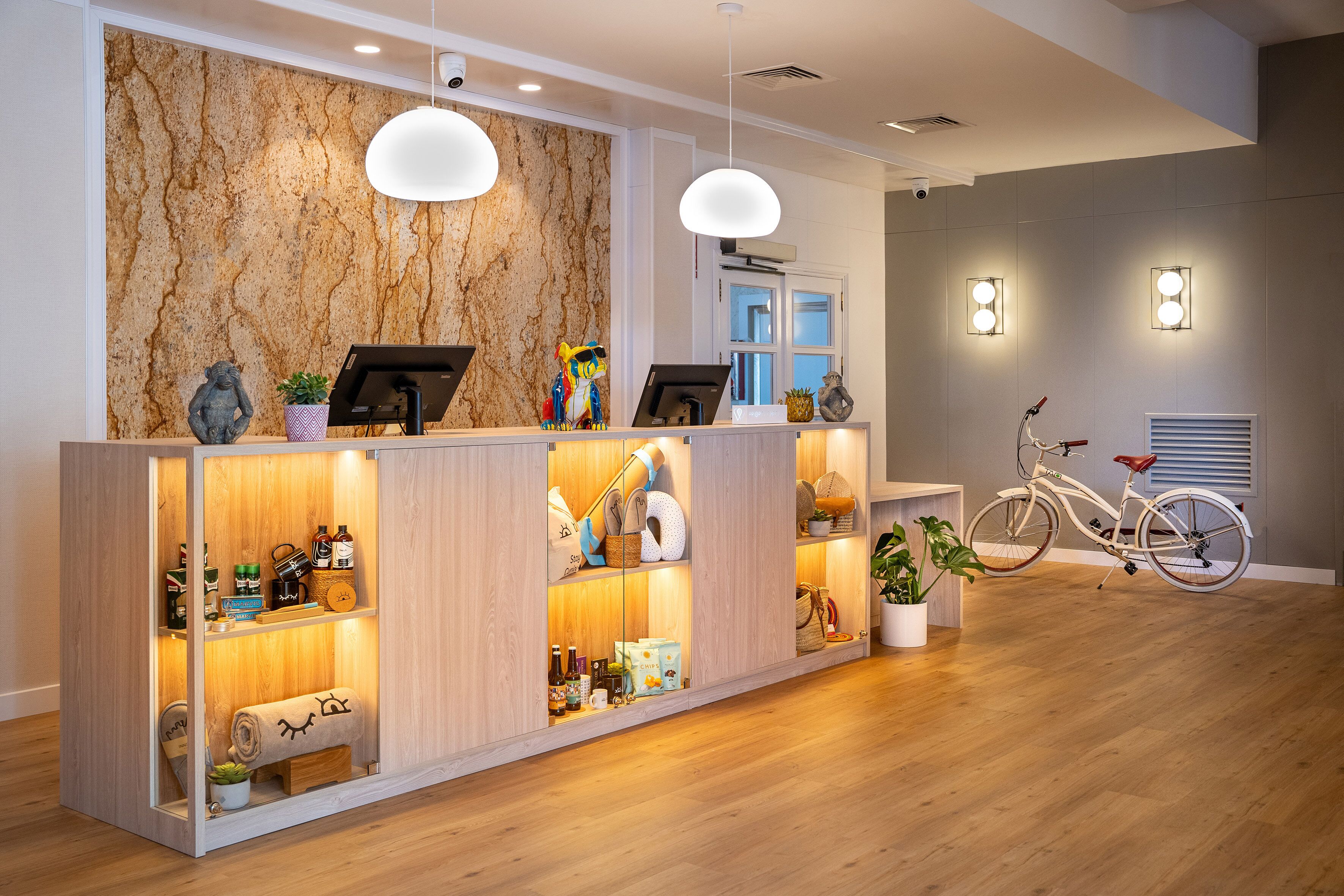 A reception desk with a wooden finish, a marble wall, and a bicycle in the background.