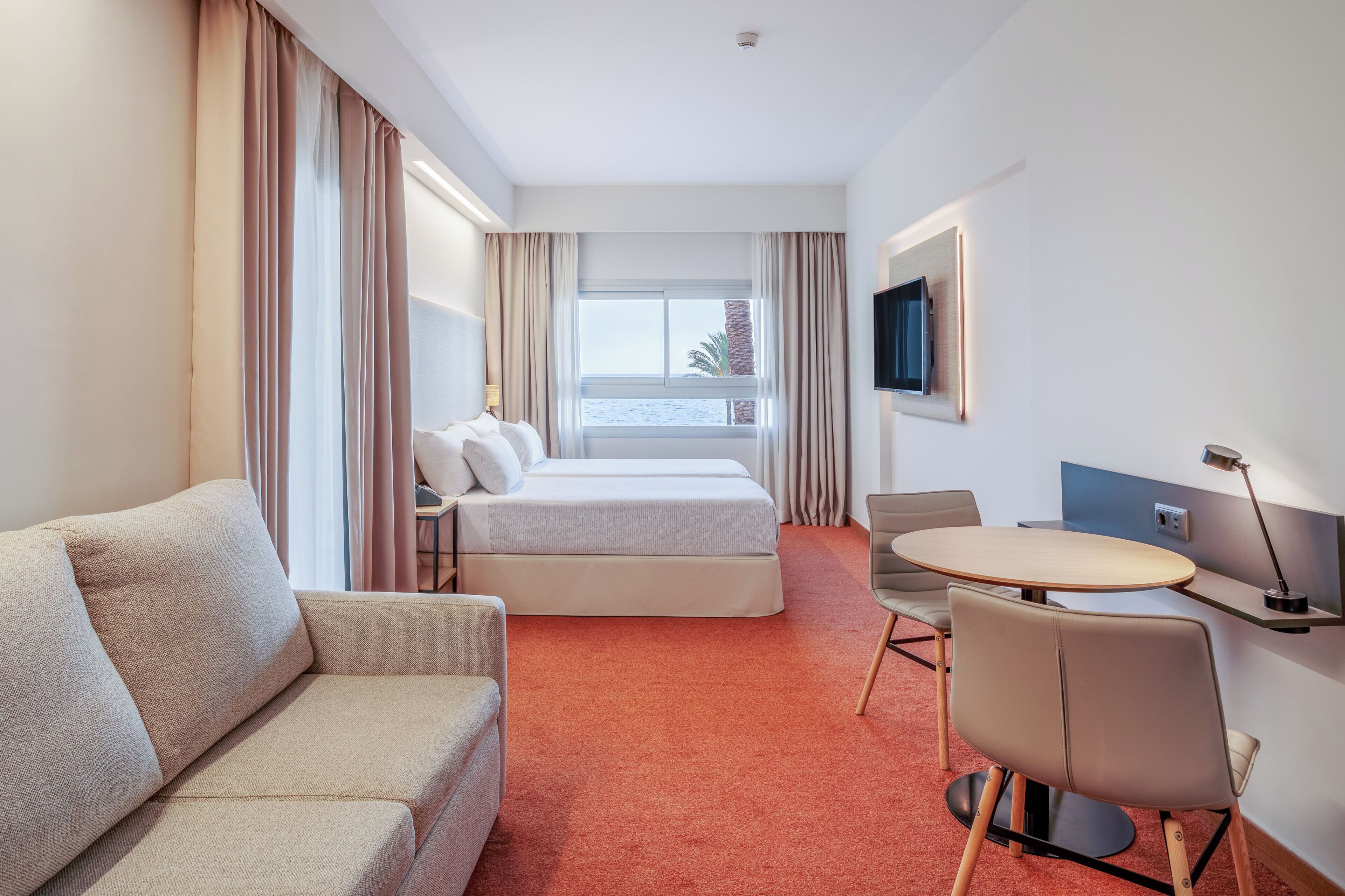 Una habitación de hotel con cama, sofá, escritorio y televisión.