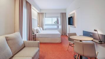 Una habitación de hotel con cama, sofá, escritorio y televisión.