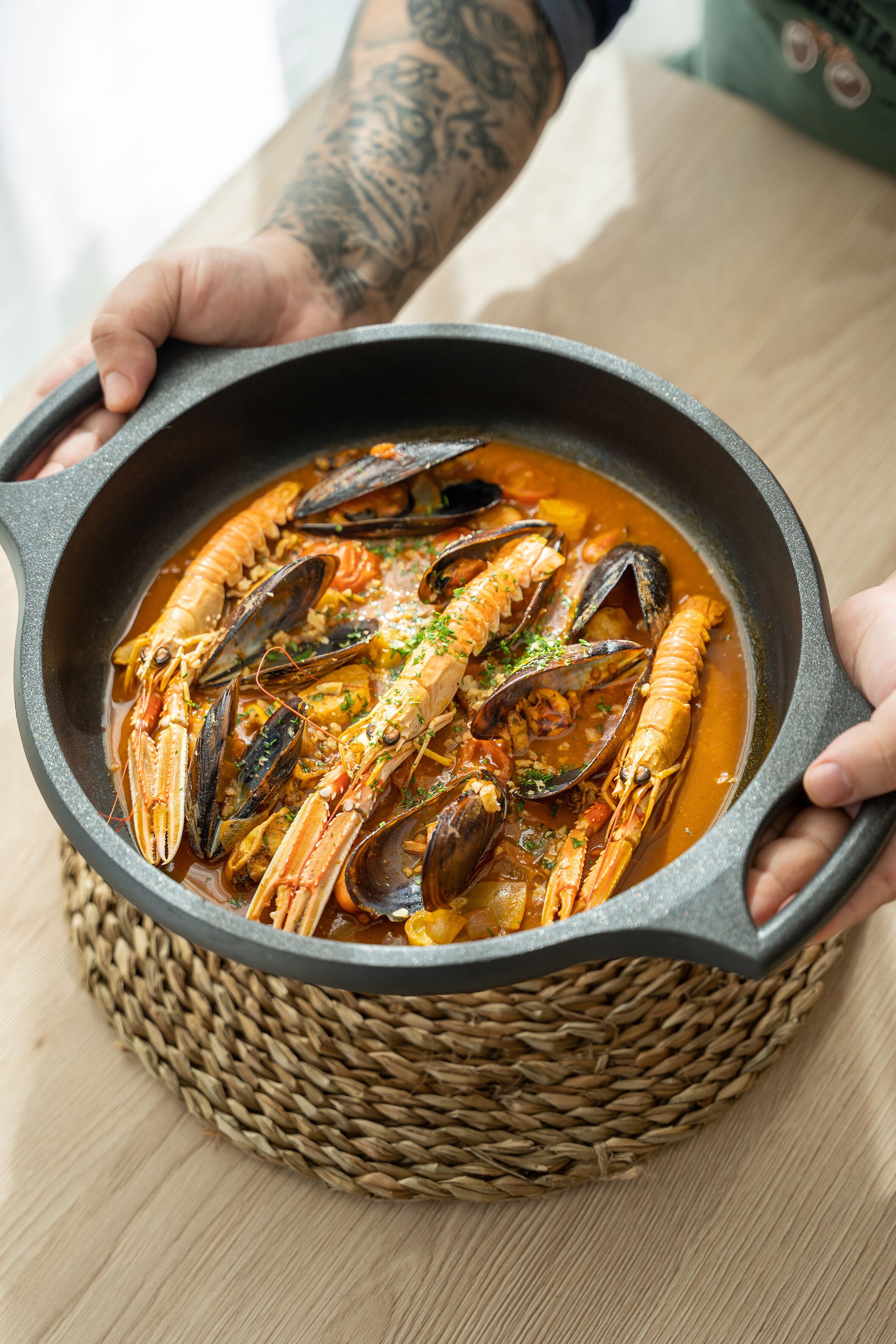A person holding a large pot of seafood stew.