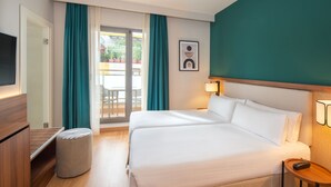 Habitació d'hotel amb un llit, una televisió, una tauleta de nit de fusta i vista a l'exterior a través d'una porta corredissa.