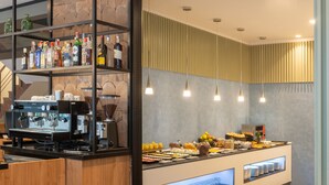 Zona de buffet amb una màquina de cafè, diferents plats i selecció de vins.