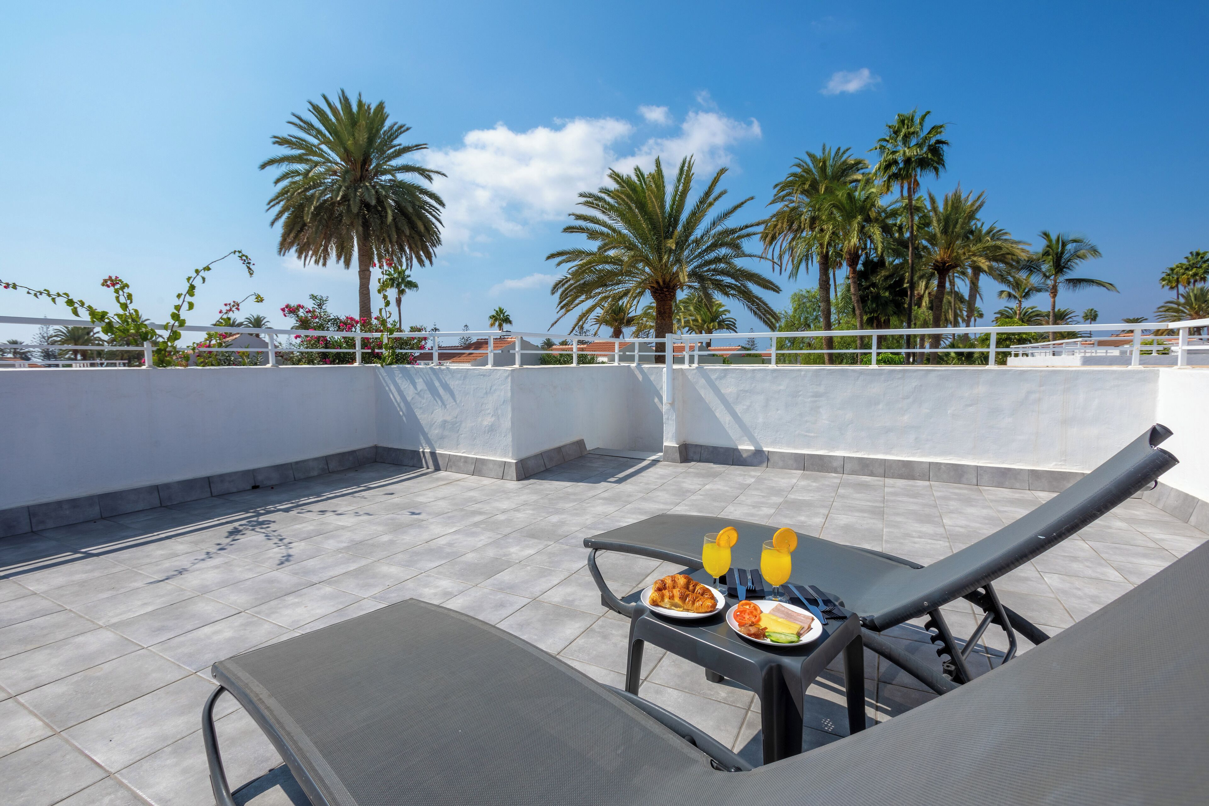 Terraza en la azotea con una mesa para dos, con un plato de comida y dos vasos de jugo de naranja.