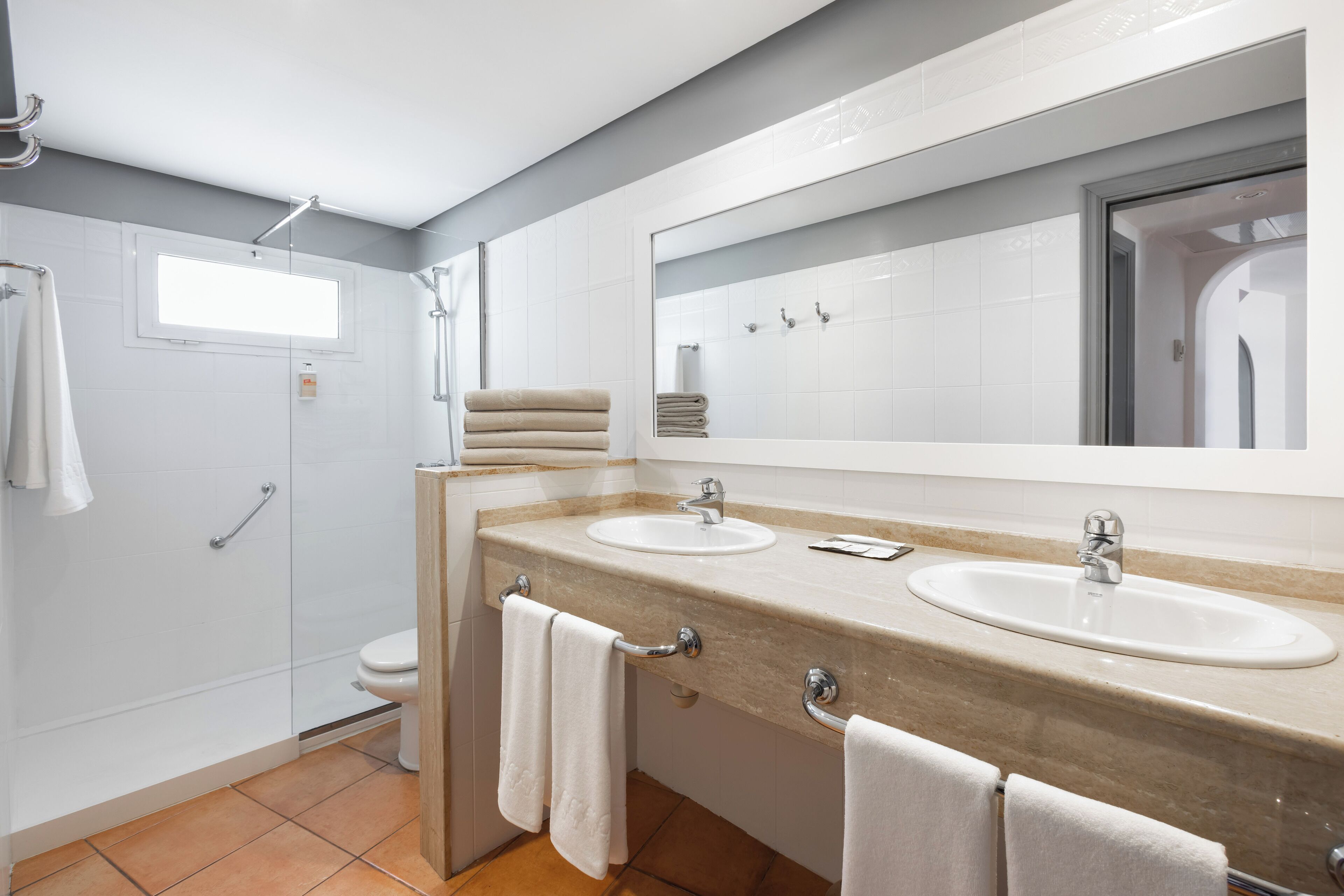 Un baño moderno con dos lavamanos, un espejo grande y una ducha.