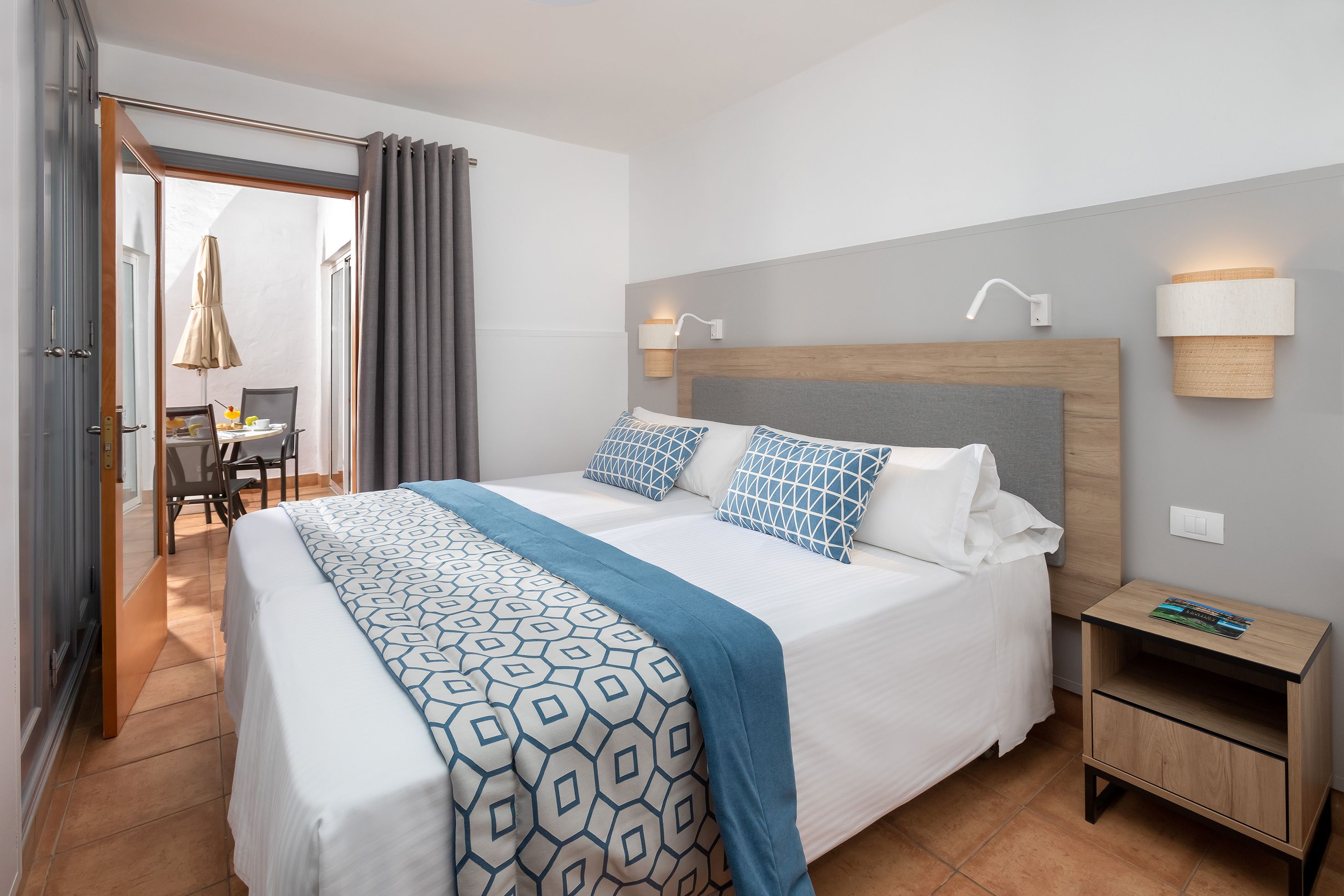 Une chambre d’hôtel avec un grand lit, une table de chevet en bois et un bureau avec une chaise.