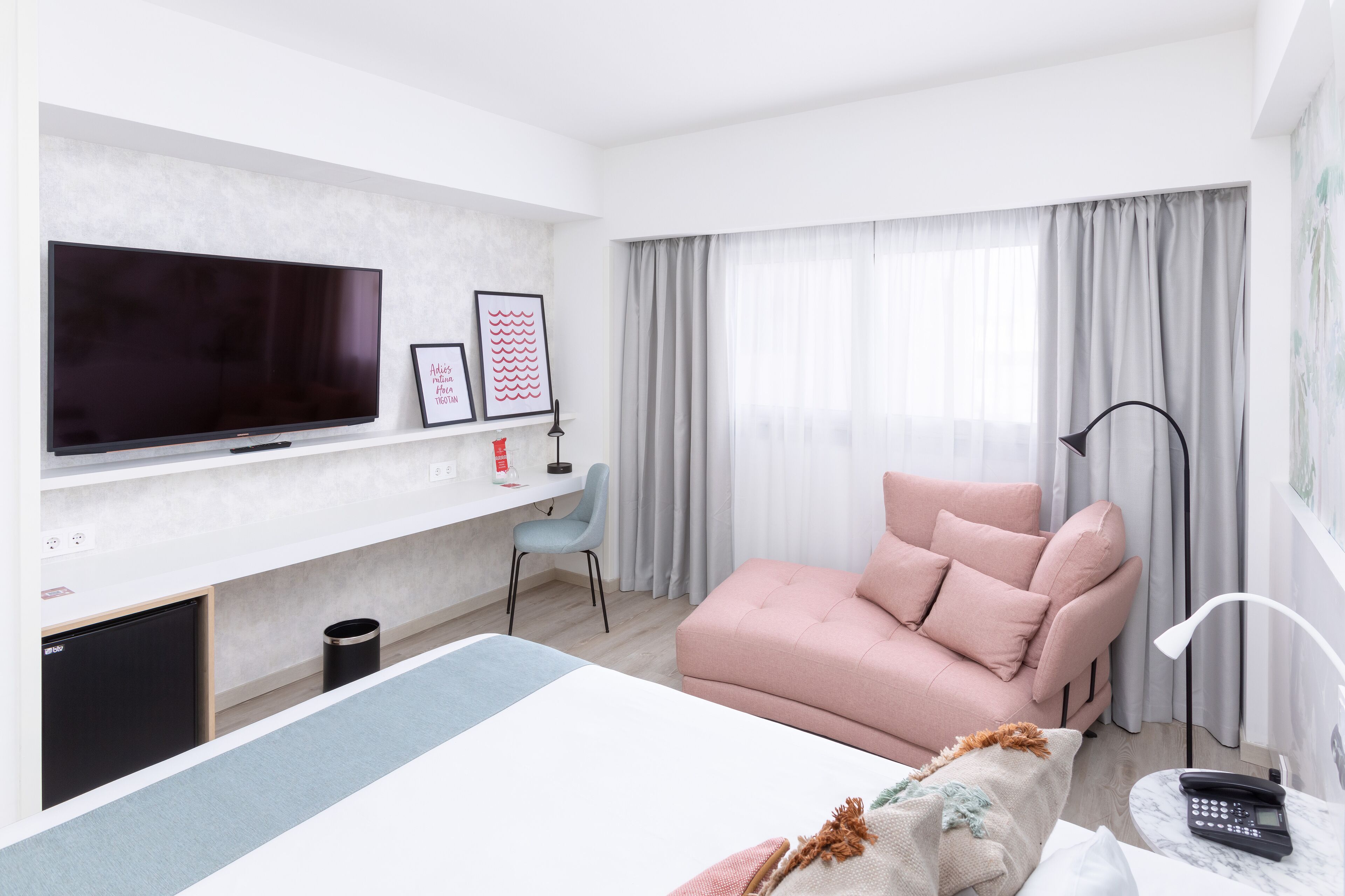 Een moderne hotelkamer met een flatscreen televisie, een bureau, een comfortabele zithoek en een bed.