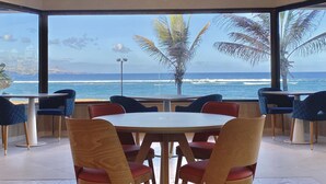 A dining area with a large window overlooking the ocean, featuring a round table and chairs.