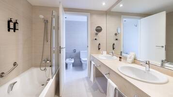 Un baño moderno con bañera, dos lavamanos, inodoro y zona de ducha.