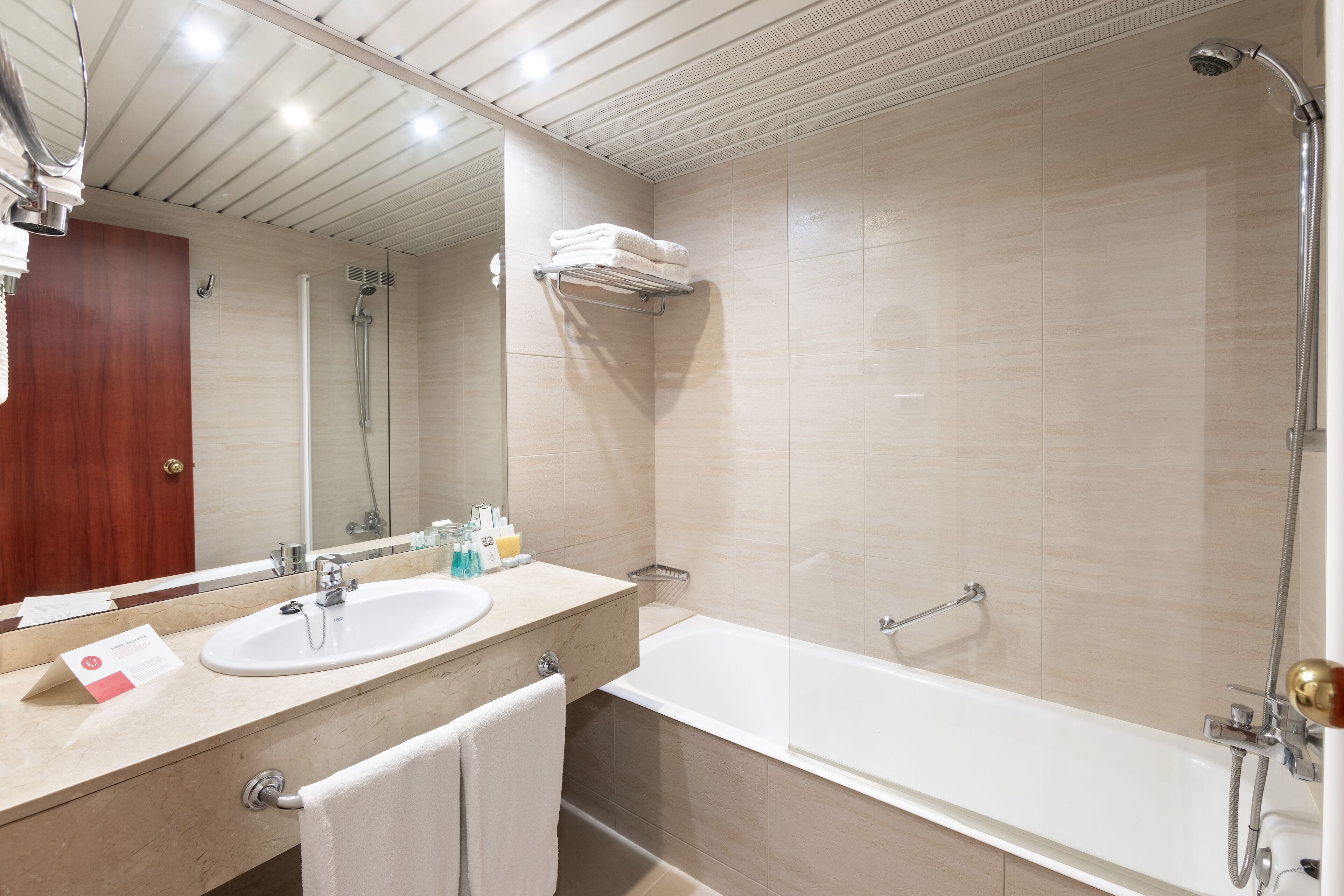 Un baño moderno con lavamanos, espejo y zona de ducha.