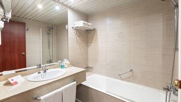 Un baño moderno con lavamanos, espejo y zona de ducha.