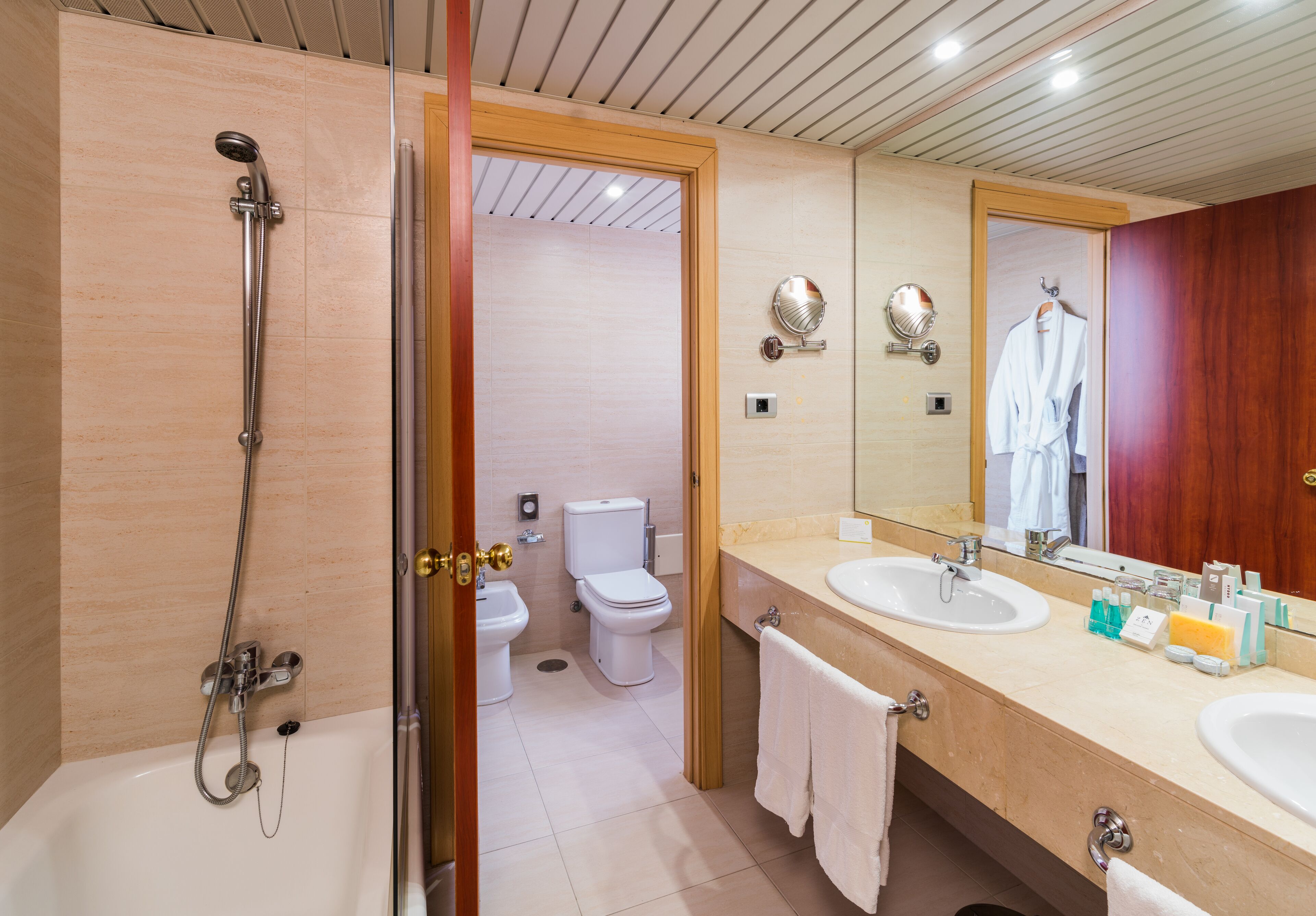Un baño moderno con bañera, dos lavamanos, un espejo y un inodoro.
