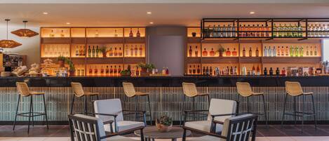 A bar area with multiple seating options and a variety of liquor bottles on shelves.
