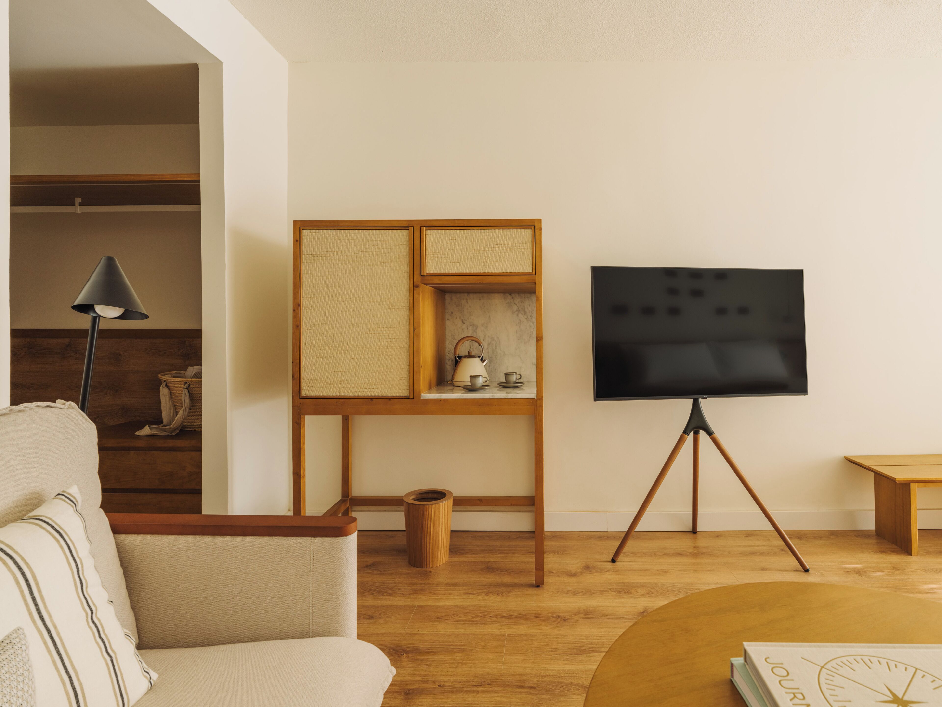 A living room with a sofa, a coffee table, a TV on a tripod stand, a bookshelf, and a lamp.