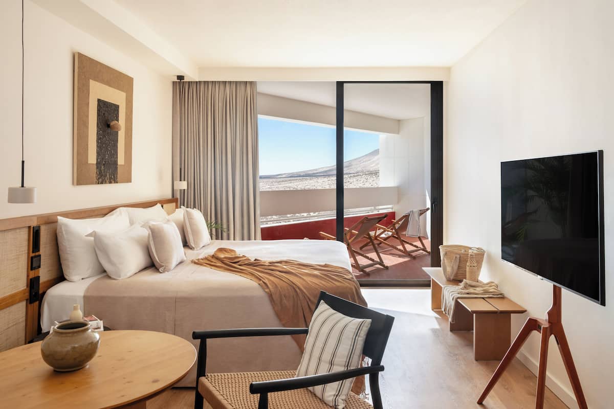 Een hotelkamer met een bed, een televisie, een balkon met uitzicht en een zithoek.