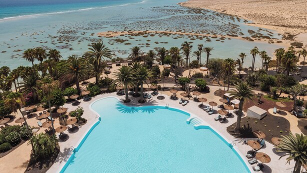 A resort with a large pool, palm trees, and a beach. - Paradisus by Meliá Fuerteventura – All Inclusive (Pajara)