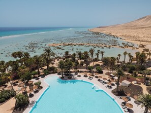 Un complexe hôtelier doté d’une grande piscine, de palmiers et d’une plage.