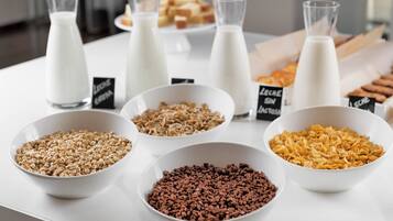 Un buffet de petit-déjeuner proposant différents types de céréales et un choix de laits.