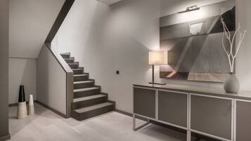 A modern staircase with a minimalist design, a console table with a lamp, and a decorative vase.