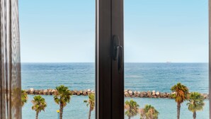 A view from inside a room with a door, overlooking a rocky shoreline with palm trees and a clear blue sky. - AC Hotel Iberia Las Palmas (Las Palmas de Gran Canaria)