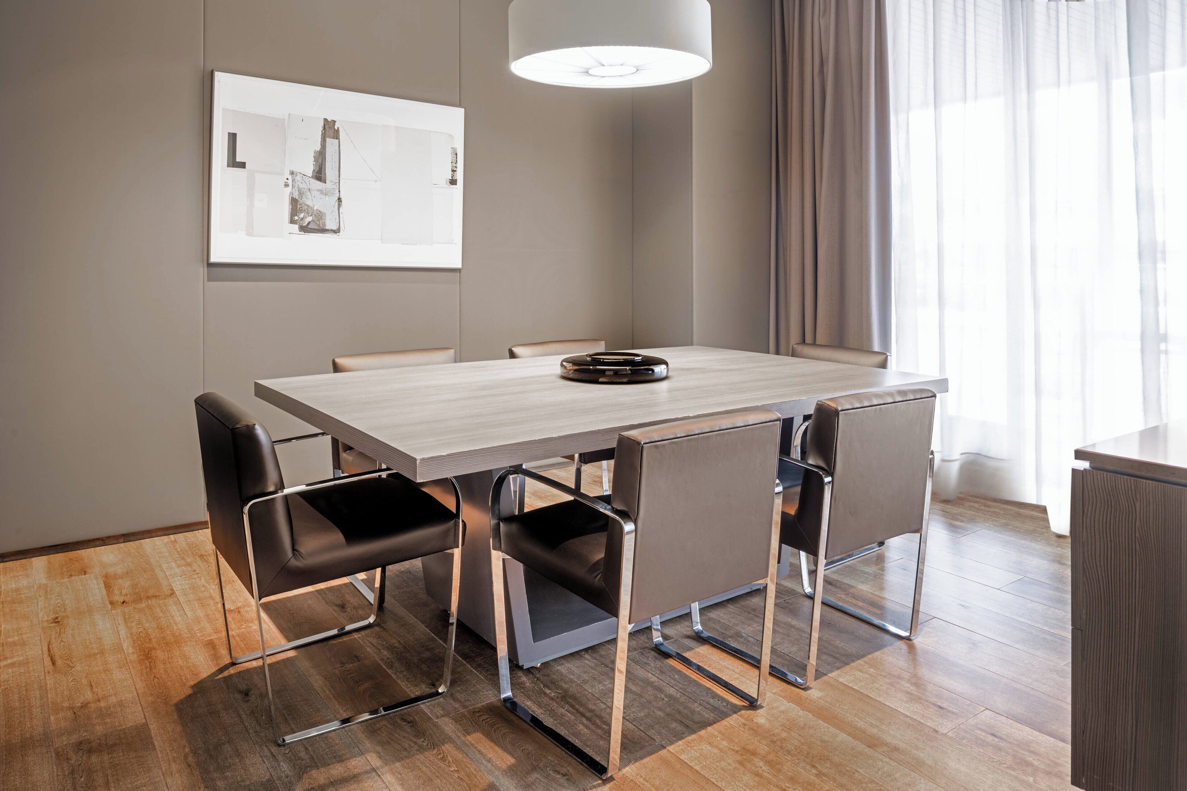 Un'area pranzo moderna con un tavolo rettangolare, sei sedie e una lampada a sospensione.