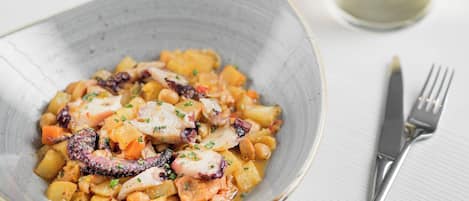 A bowl of food with a fork and knife beside it.