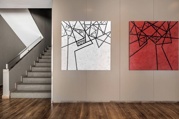 A staircase leading to a landing with two abstract paintings on the wall.