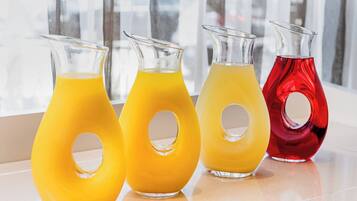 Quatre carafes en verre contenant différents liquides de couleurs variées, posées sur une surface réfléchissante.
