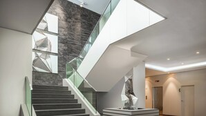 A modern interior with a staircase, glass railings, and a geometric sculpture. - AC Hotel Iberia Las Palmas (Las Palmas de Gran Canaria)