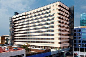 Ein mehrstöckiges Hotel mit modernem Design, das eine Reihe von Balkonen und eine Dachterrasse bietet.